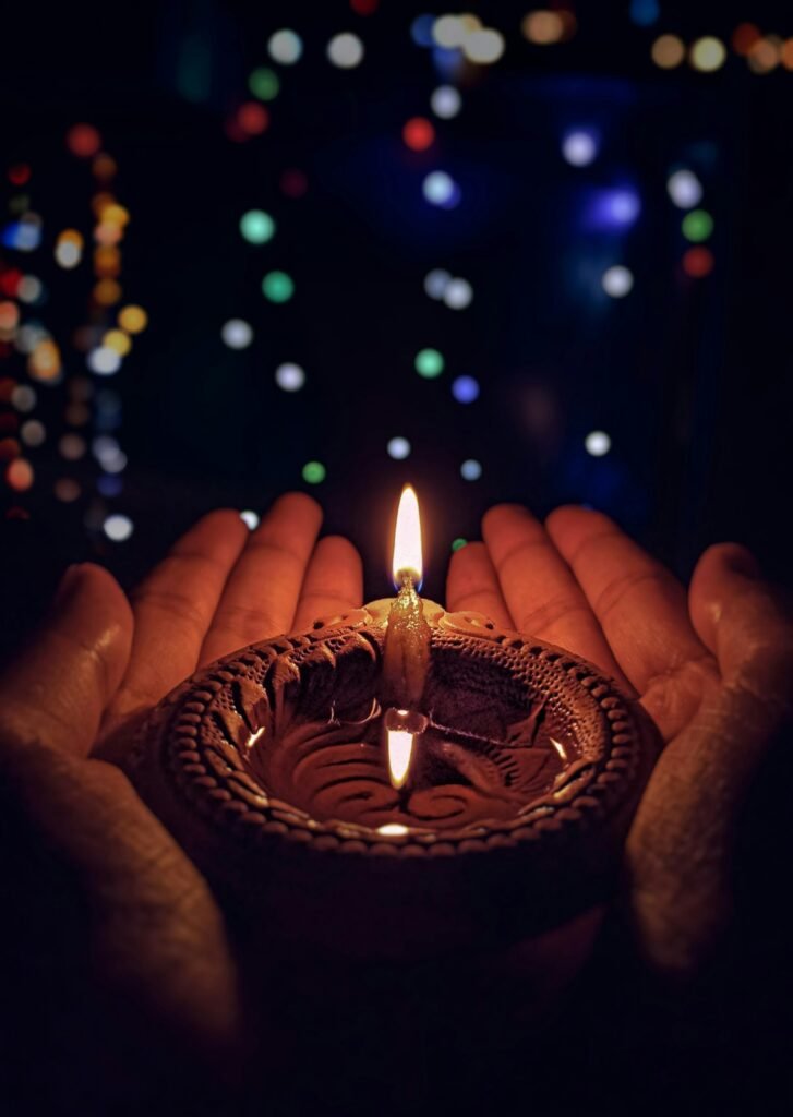Hands holding a lit diya